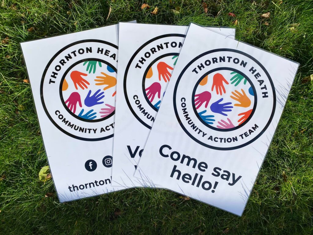 Three THCAT come say hello posters displayed in a fan laying on grass